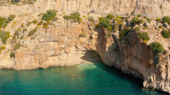 A Couple of Travelers Swims in a Hidden Cove with a Cave in Mountain on the Road From Demre