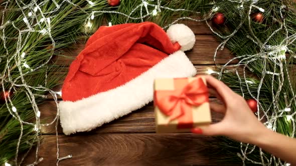 Woman Hands Putting a Gift Box on Table with New Year Decorations