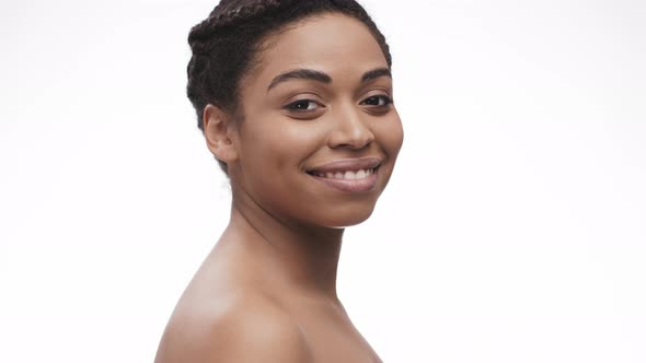 Back View of Young Nude African American Lady Turning To Camera and Smiling White Studio Background