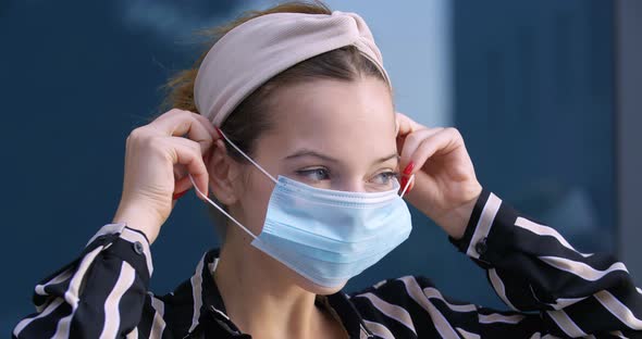 Close-up of Woman Puts on Blue Medical Protective Surgical Mask on Young Female Face, Portrait