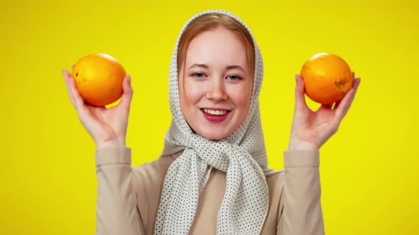 Joyful Slim Redhead Woman with Green Eyes Hiding Face with Two Oranges Smiling