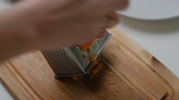 Close-up of  Female hands grate carrots on white table. Top view Cooking Salad.