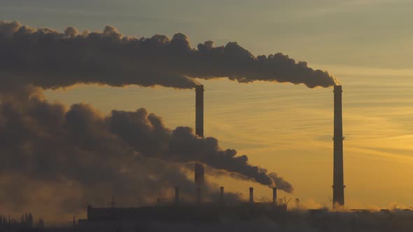 Smoke from industry plant chimney over sunrise sky background