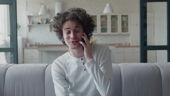 Curlyhaired Teenager with a Nose Piercing and Tunnels in His Ears Talking on Smartphone While