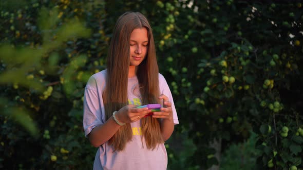 A Girl with Long Hair Plays Popit in Nature