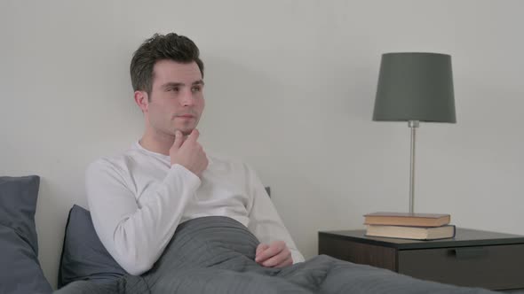 Man Thinking While Sitting in Bed