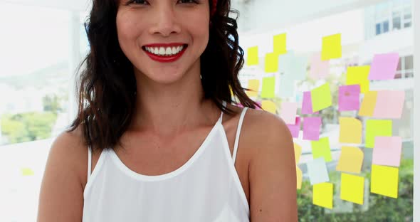 Smiling female executive standing with arms crossed in office 4k