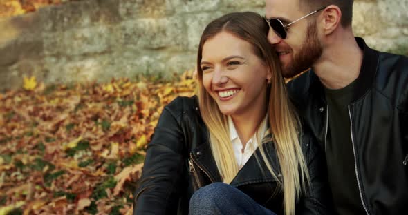 Man in Sunglasses Caresses His Smiling Girl When They Relaxing on Autumn Nature