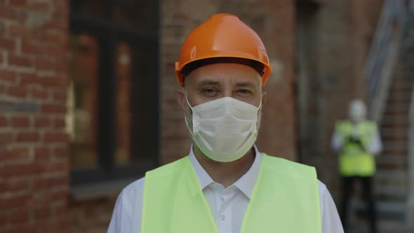 Portrait of Builder in Hardhat and Medical Mask Outdoor