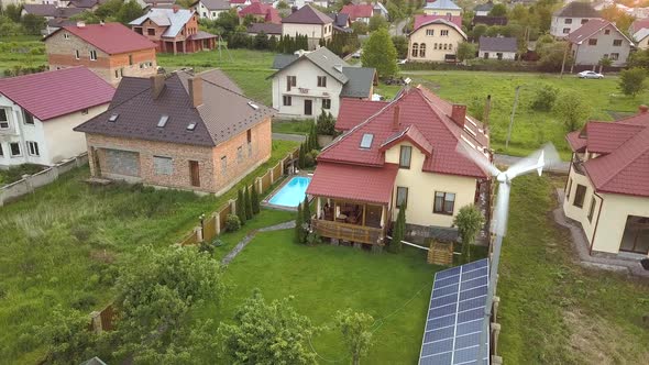 Aerial View of Suburban Homes and Private House with Green Grass Covered Yard Solar Panels on Roof