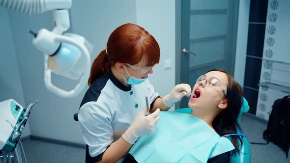 Woman in stomatology clinic. Stomatology doctor treating woman teeth in dentistry clinic