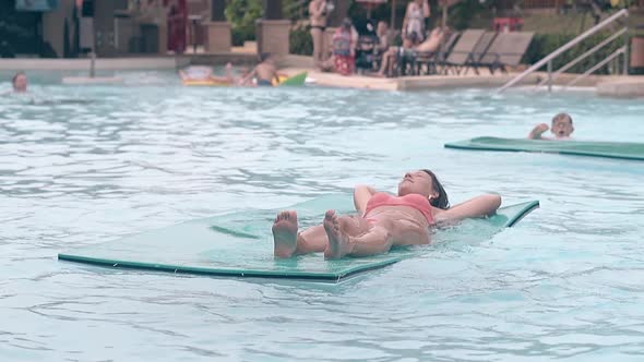 Young Lady Lies on Swimming Mat in Hotel Pool Slow Motion