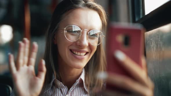 A Young Smiling Woman is Having a Video Call During Riding in Public Transport