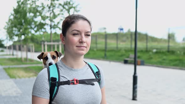 Caucasian Woman Walking Outdoors with Dog Jack Russell Terrier in a Special Backpack