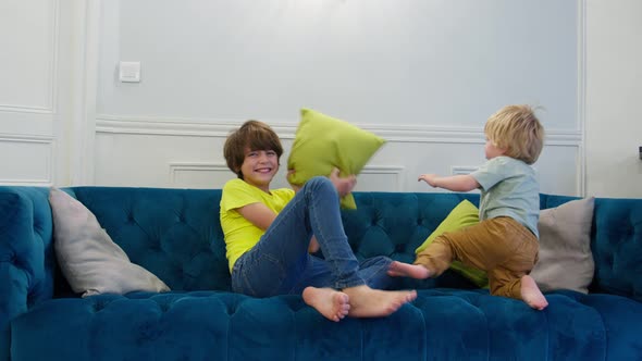 Blond Boy and Brother Fight with Pillows at Home