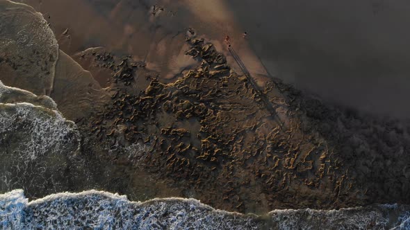 Picturesque rocky pattern and design seabed by Calheta sandy shore beach with ocean sea waves rollin