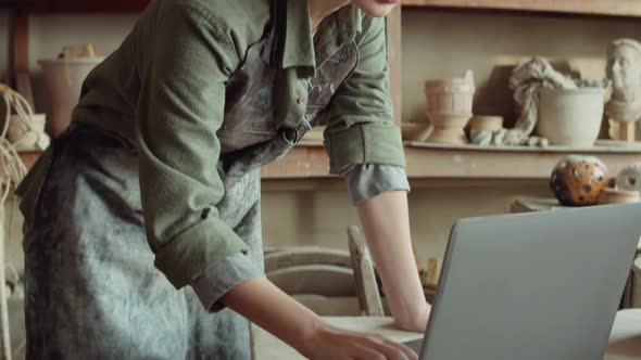 Woman Using Laptop in Pottery Workshop