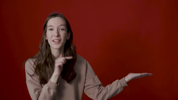 A Positive Young Woman Points Her Fingers to the Side Indicating a Place for your Advertisement