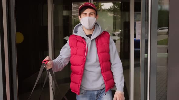 Delivery Man in Face Mask Carrying Bag with Orders