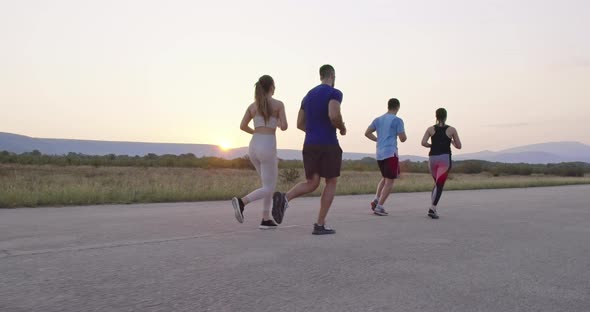 Multiethnic Group of Athletes Running Together on a Panoramic Countryside Road