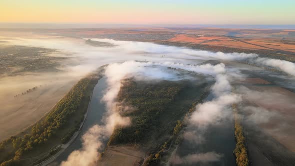 Aerial drone view of nature of Moldova at sunset. River and lush fog above it, village, greenery