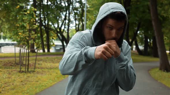 Young Fighter in Gray Hook Running at Park and Brandish Hands Like Boxer