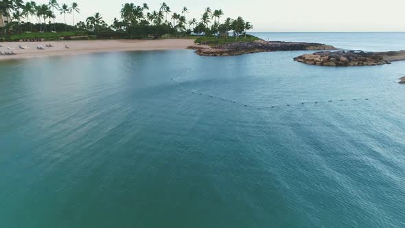 Aerial view scenic bay water surrounded by Rocky pontoon, palm trees coastline