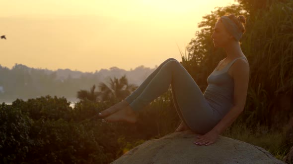 Girl Stands in Navasana on Large Rock at Sunrise Slow Motion