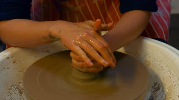 Hands of male potter assisting female potter