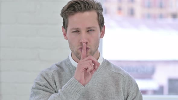 Portrait of Creative Young Man Putting Finger on Lips