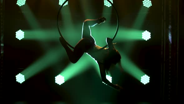 Silhouette of Air Gymnastics Performs Acrobatics Tricks on Aerial Hoop. Exciting Acrobatic Show in a