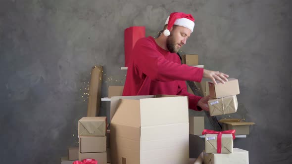 Caucasian Male Businessman Wearing Red Santa Claus Hat Stacks Craft Boxes with Barcode