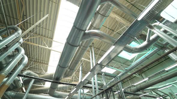 Pipes of the ventilation system are located on the ceiling of plant with the production of parquet.