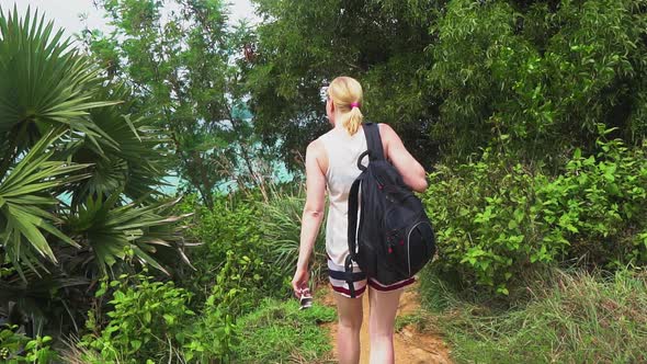 tourist woman with a backpack walking on a tropical forest on the island