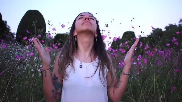 young latin woman grateful with god in the middle of a beautiful purple field with tinny flowers.