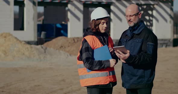 Concentrated Engineers Discussing Examining and Developing at Construction Site