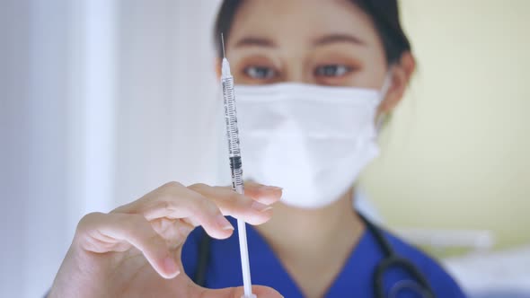 Close Up Female Asian Nurse Doctor Holding a Vaccine Injection Needle Ready for Vaccination at Work
