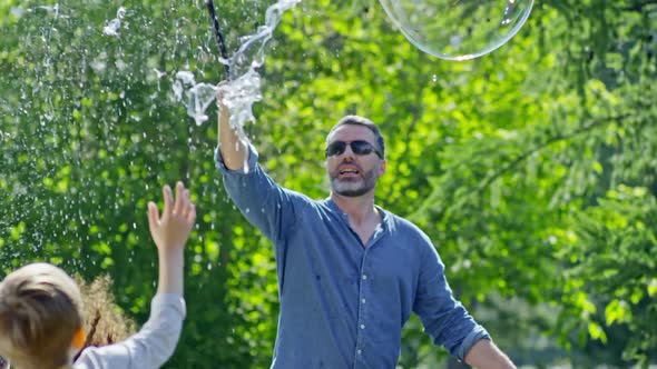 Kids Enjoying Popping Huge Bubble at Performance in Park alt