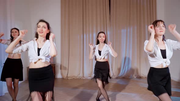 Four Girls in Black Skirts and White Shirts are Dancing Indoors