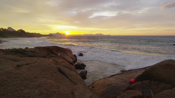 Waves breaking on shore rocks at sunset