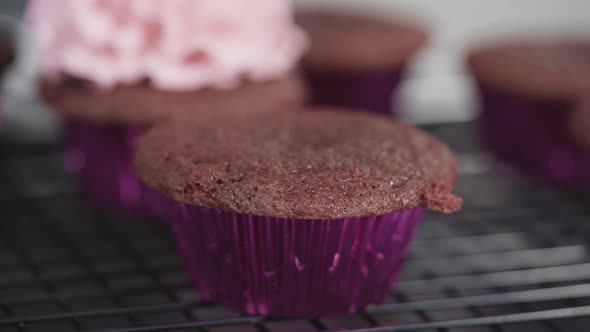 Step by step. Piping Italian buttercream frosting on top of red velvet cupcakes.