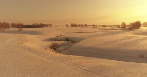 Aerial View of Cold Arctic Field Landscape Trees with Frost Snow Ice River and Sun Rays Over Horizon