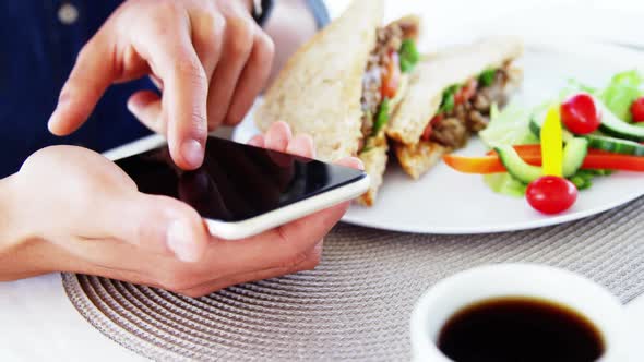Man in lunch bar with smartphone and coffee