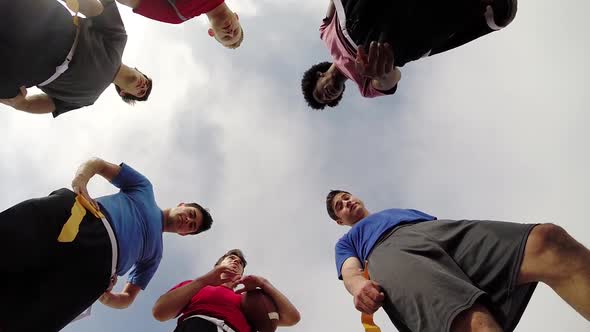 A group of young men playing flag football on the beach.