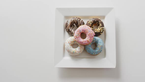 Video of donuts with icing on white plate over white background