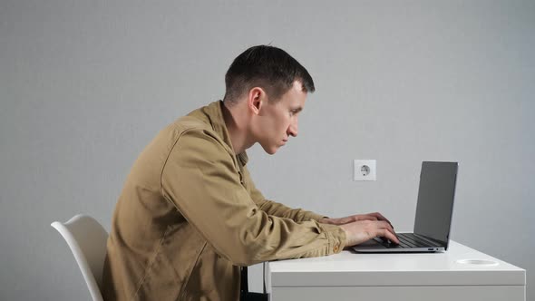 Man Employee with Crooked Neck Works on Laptop in Office