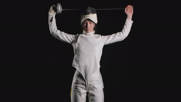 Portrait of Confident Young Woman Fencer. A Sportswoman in a White Suit with a Sword in Her Hands