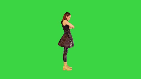 Gamecharacter Girl with a Gun on Belt Stands Folding Her Arms in Threatening Manner on a Green