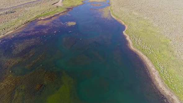 Aerial view flying over river inlet as it flows into lake