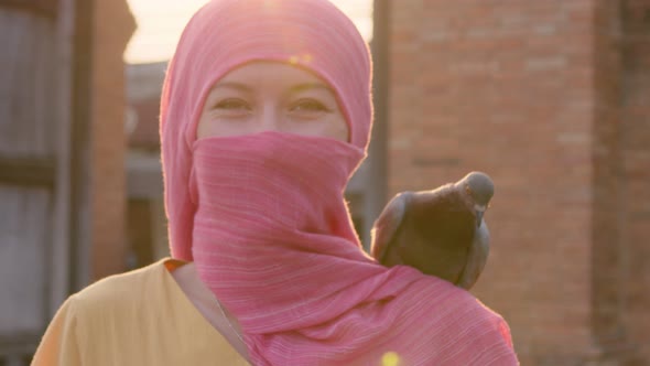 Attractive Muslim Woman with Natural Makeup Wearing a Pink Hijab Scarf Standing with a Sun on a